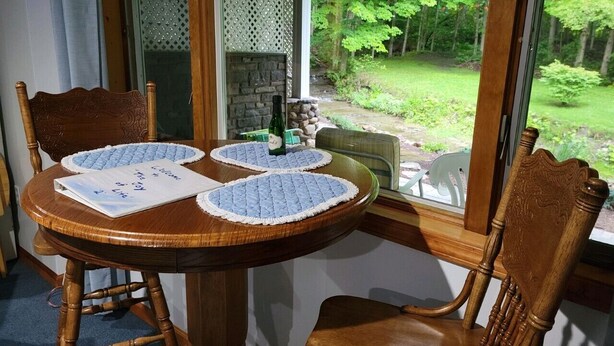 Een houten eettafel met vier stoelen, een fles en een menukaart.
