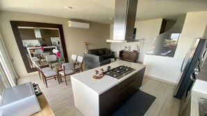 Une cuisine moderne dotée d’un îlot central, d’appareils électroménagers intégrés et d’un coin repas avec des chaises et une table.