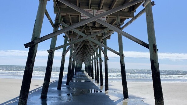 A wooden pier extending into the ocean with a clear sky above. - Sunset Beach, on the golf course, pet friendly. (Sunset Beach)