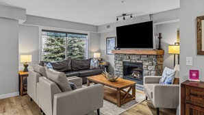 A living room with a stone fireplace, a flat-screen TV, a sofa, and a coffee table.