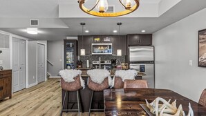 A modern kitchen with dark cabinets, a stainless steel refrigerator, and a central island with bar stools.