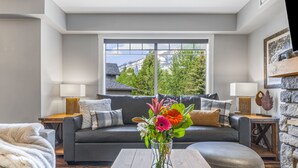 A modern living room with a grey sofa, a wooden coffee table, and a vase of flowers.