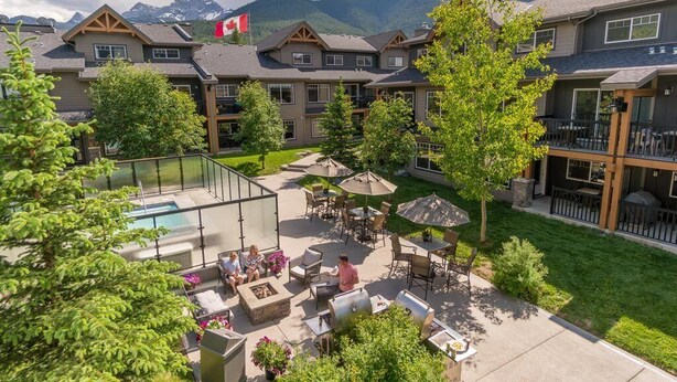 A resort with a pool, outdoor seating, and mountain views.