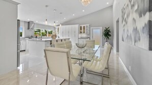 A modern kitchen with white cabinets, a central island, and pendant lighting. - Luxury Unique Property 4-3 - Entire House - Heated Pool - Lg Yard (West Palm Beach)