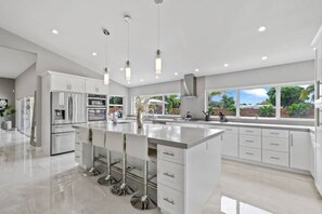 Een moderne keuken met een centraal eiland, roestvrijstalen apparatuur en een groot raam met uitzicht op de omgeving.