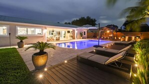 A modern house with a swimming pool, outdoor seating, and a well-lit patio area. - Luxury Unique Property 4-3 - Entire House - Heated Pool - Lg Yard (West Palm Beach)