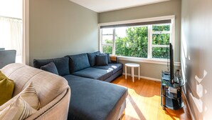 Ein modernes Wohnzimmer mit einer Eckcouch, einem kleinen runden Tisch und einem Fernsehschrank.