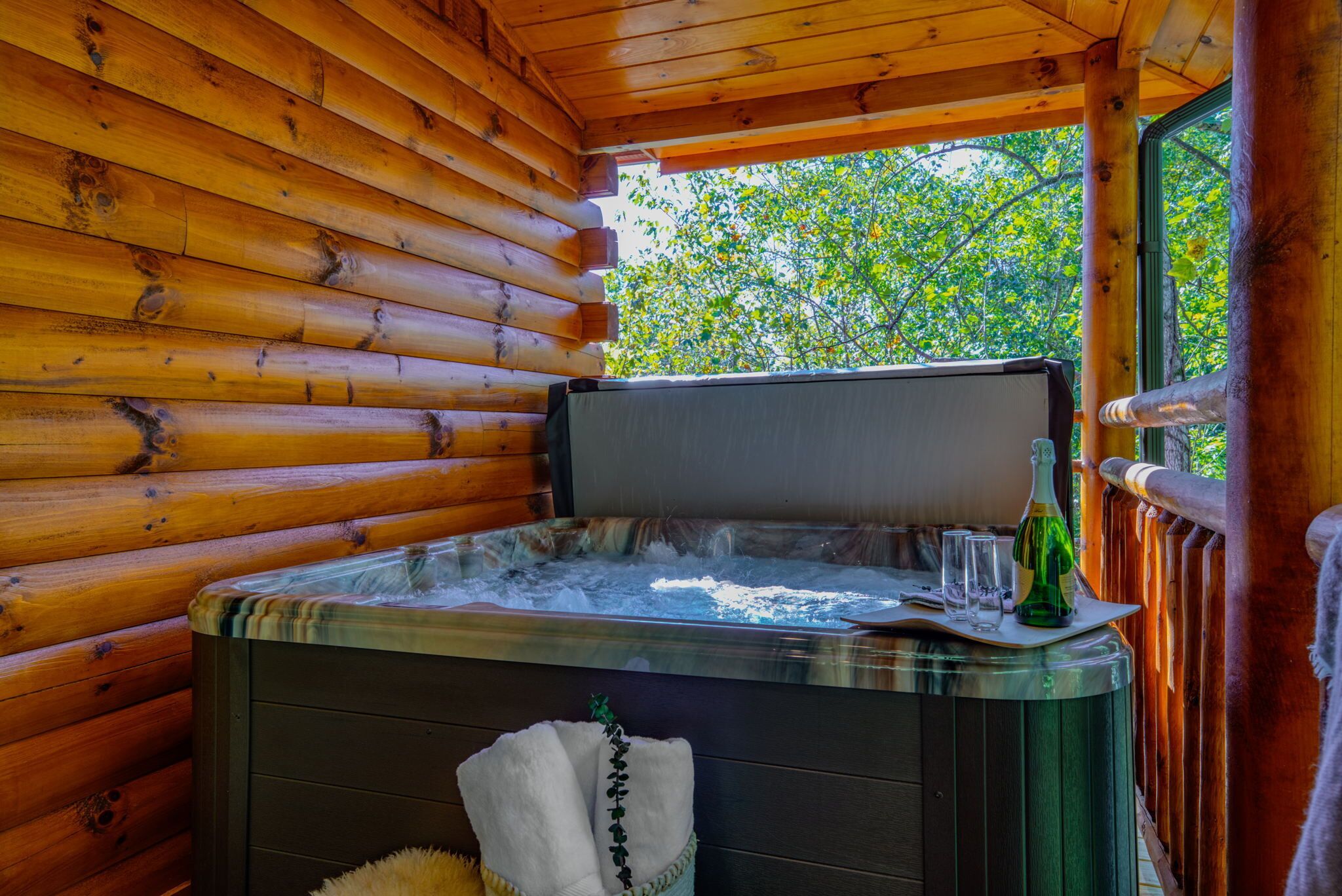 Eine Holzhütte mit Whirlpool, einer Weinflasche und einem Handtuch auf dem Boden.