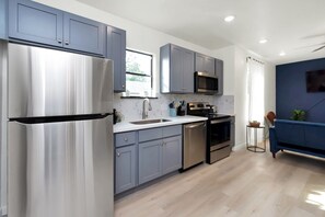 Uma cozinha moderna com armários cinza, eletrodomésticos de aço inoxidável e uma parede azul de destaque.