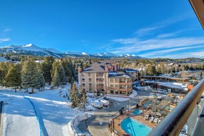 A hotel with a pool, surrounded by snow-covered mountains and trees. - Village at Breckenridge - Shavano Unit 2603 Ski In/Out (Breckenridge)
