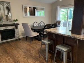 A dining area with a stone fireplace, a large mirror, and a view of the outdoors through a window. - BEAUTIFUL centrally located southhill home close to hospitals and parks (Spokane)