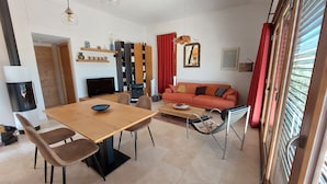 Un salon moderne avec une table à manger en bois, un canapé et un téléviseur.