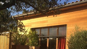 Une terrasse en bois avec un banc, une bouteille en verre et une plante en pot.