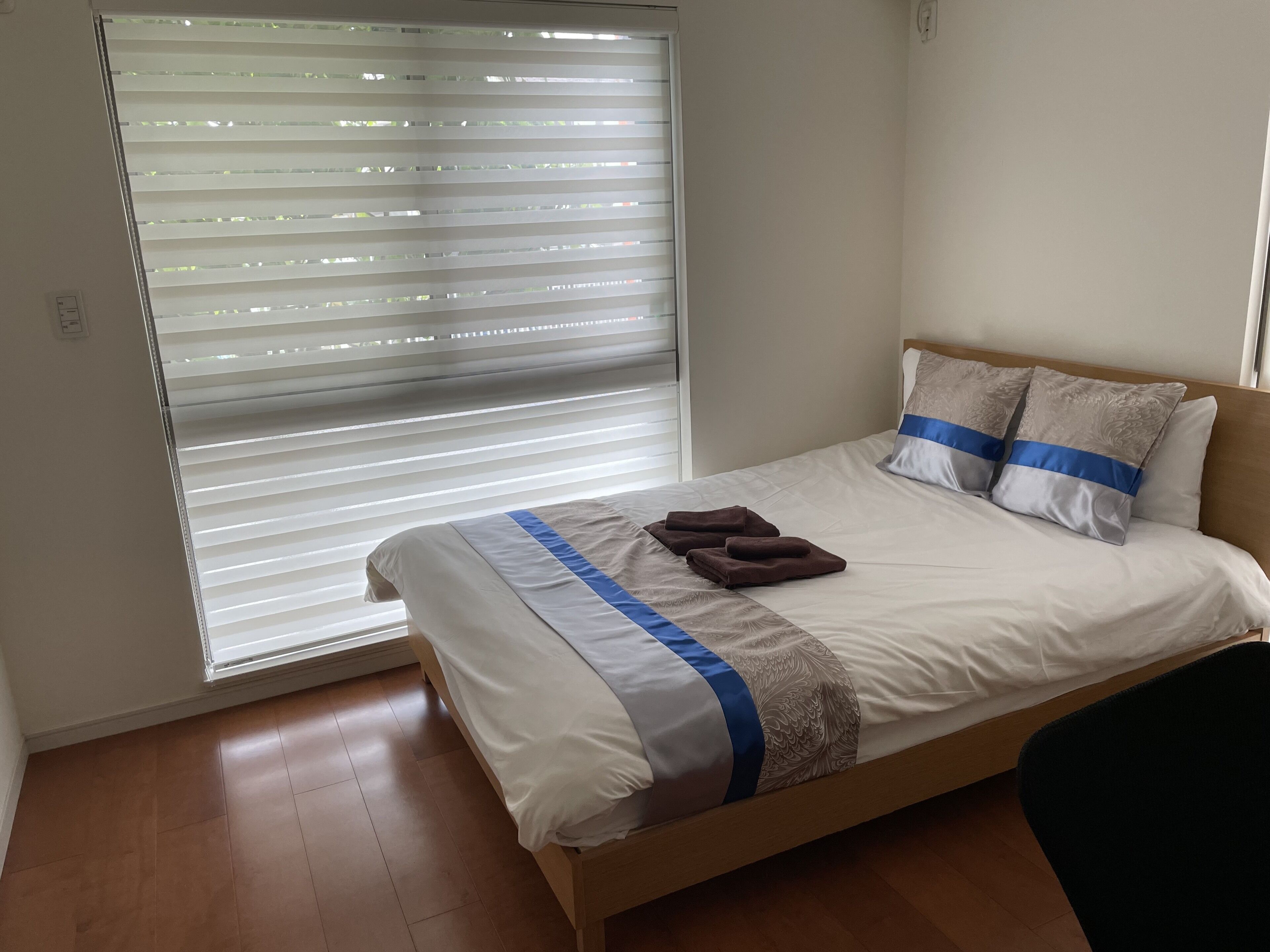 A neatly made bed with a blue and white striped bedspread, two pillows, and a folded towel.