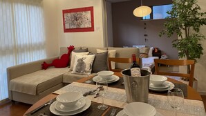 A dining area with a table set for four, a sofa with cushions, a red decorative item, a wall-mounted artwork, and a potted plant. - Skytree House In Tokyo (Tokyo)