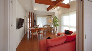 A spacious living area with a red sofa, dining table, and chairs. There is a potted plant and a ceiling fan. - Skytree House In Tokyo (Tokyo)