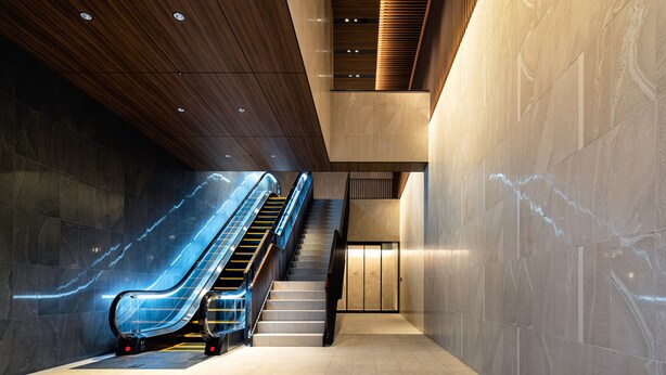 Een modern interieur met een glazen lift, een trap en een houten plafond.