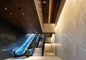 A modern interior with a glass elevator, a staircase, and a wooden ceiling. - Daiwa Roynet Hotel Morioka Ekimae (Morioka)