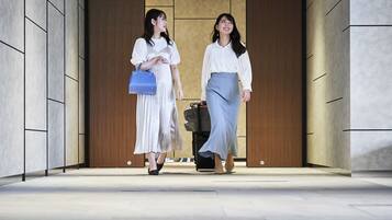 Two individuals walking through a hallway with a modern design, featuring a combination of wood and stone elements.