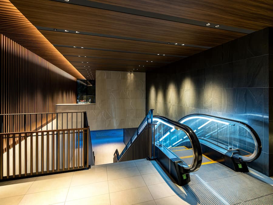 An indoor escalator in a modern building with wooden paneling and a tiled floor.