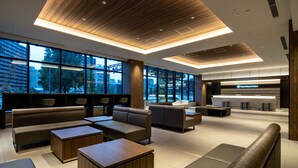 Een moderne hotellobby met zithoeken, grote ramen en een zichtbare receptiebalie.