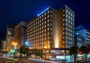 Un hotel moderno con un cartel llamativo, varios pisos y una fachada bien iluminada.