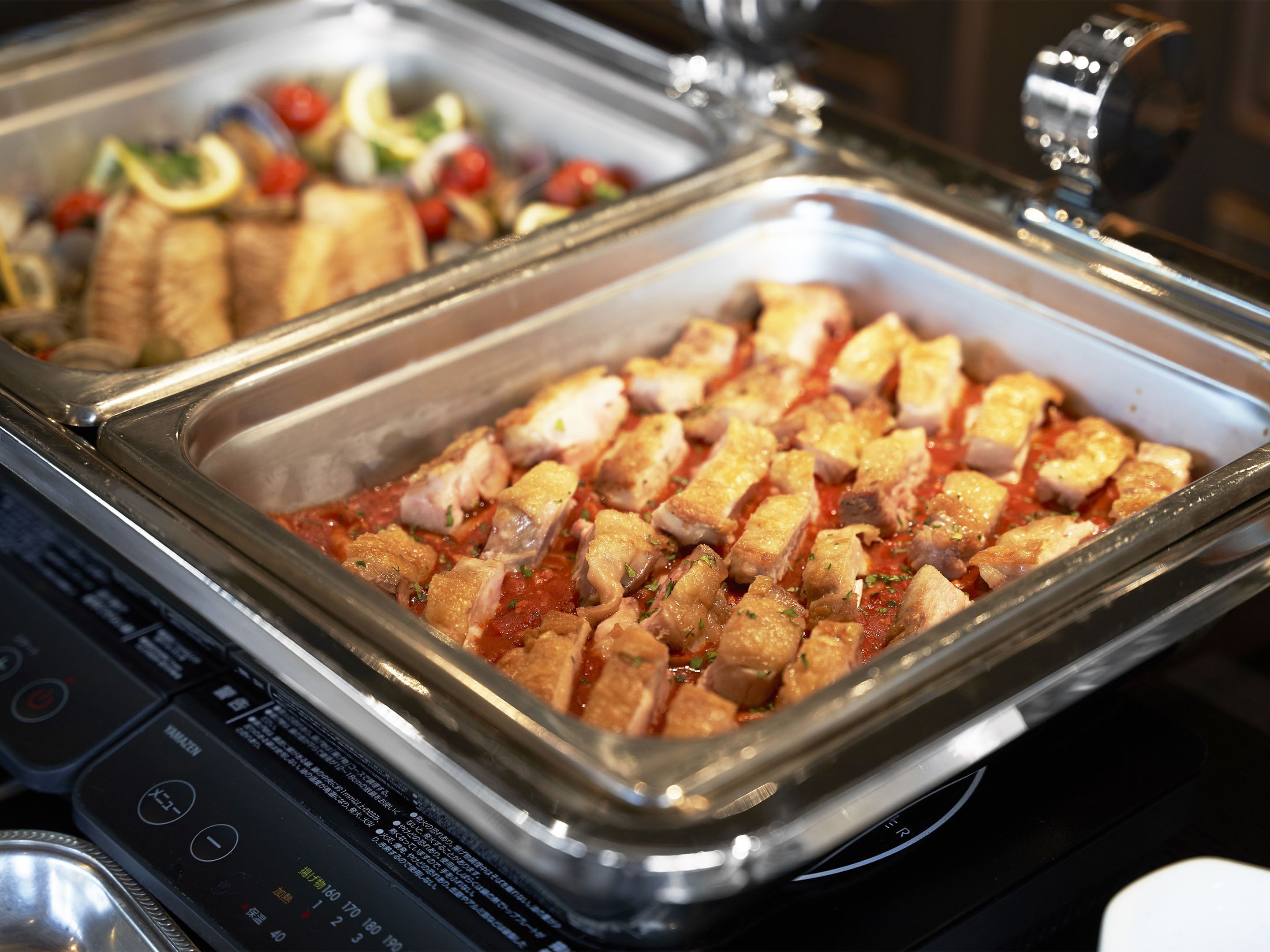 A buffet with various dishes including cubed meat and vegetables.