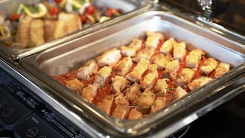 A buffet with various dishes including cubed meat and vegetables.