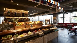 Een bar met diverse eet- en drinkmogelijkheden, waaronder een selectie ambachtelijke biertjes en een buffet met fruit en kazen.