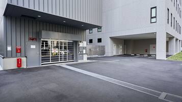 A modern building with a gated entrance, emergency equipment, and a parking area.