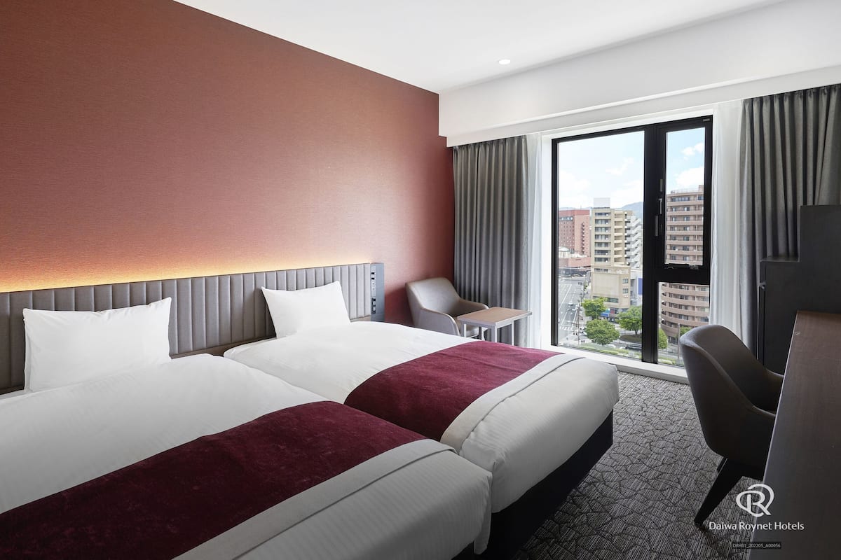 Une chambre d’hôtel avec un grand lit, un bureau et une vue sur la ville.