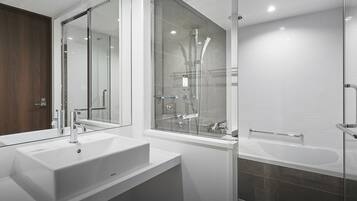 A modern bathroom with a large mirror, a white sink, and a glass-enclosed shower area.