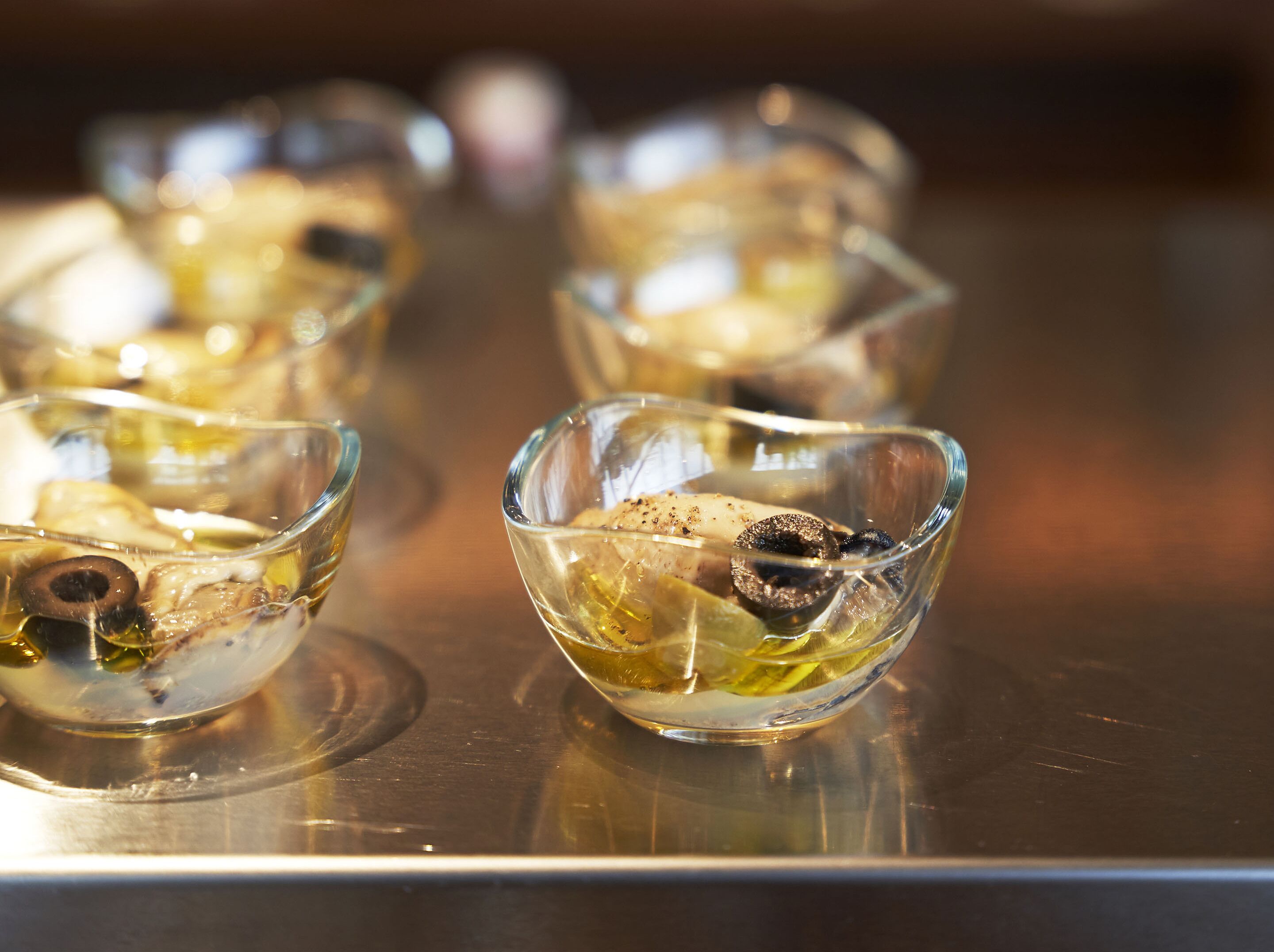 A close-up of several glass bowls containing food items on a metallic surface.