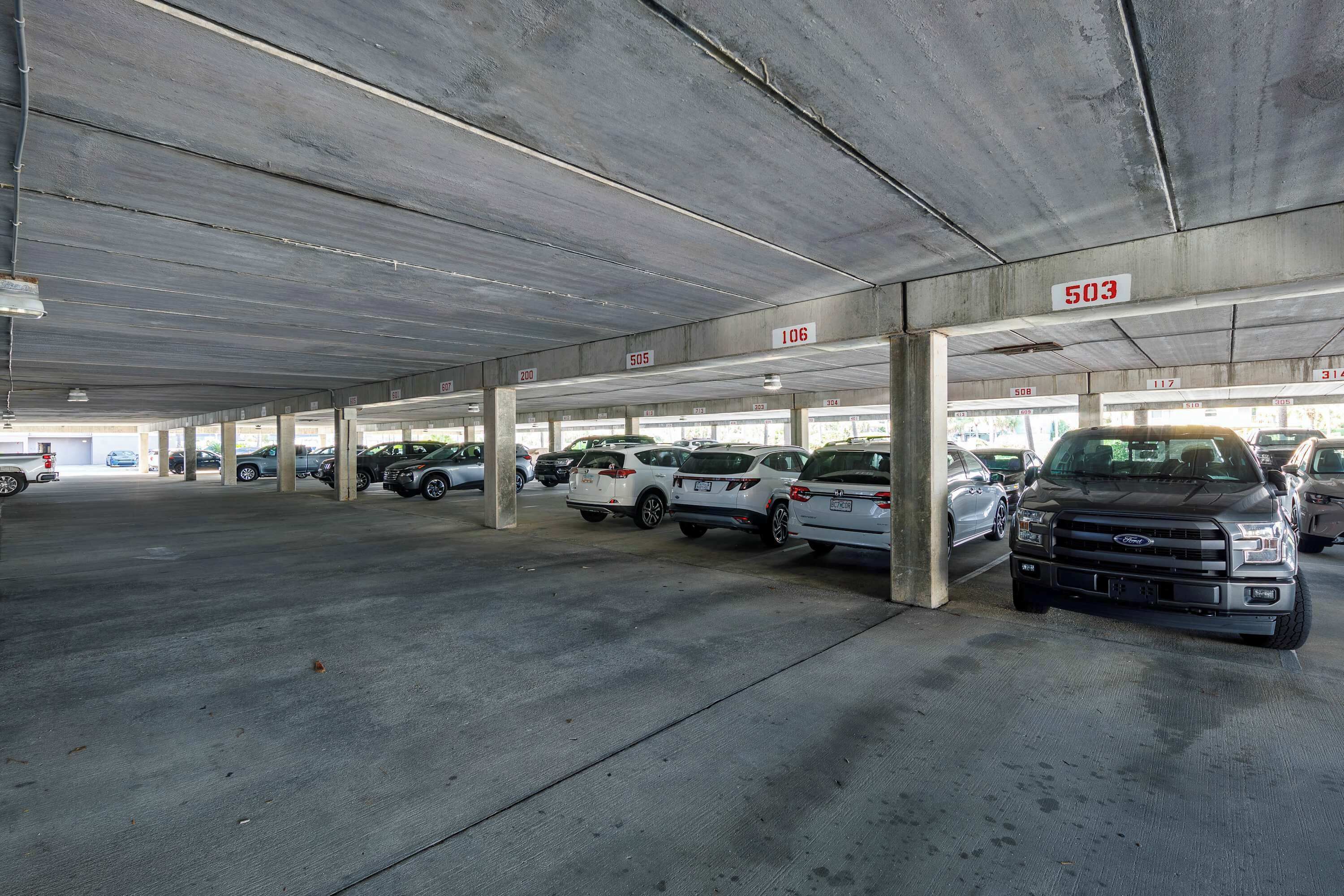 A multi-level parking garage with concrete pillars and numbered parking spaces.