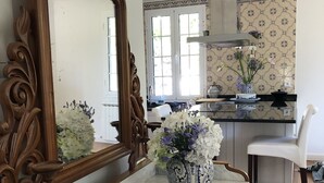 A kitchen with a marble countertop, a large ornate mirror, a vase with flowers, and a white chair. - The Garden of Paradise (Santa Cruz)