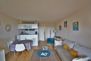 Ein kompakter Wohnraum mit Essbereich, Küchenzeile und einer Couch mit Kissen.