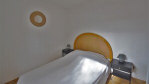 Makuuhuone, jossa on sänky, yöpöytä, lamppu ja pyöreä seinäkoriste.