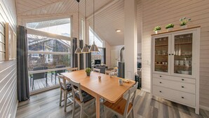 A modern kitchen with a wooden table, chairs, a stove, and a cabinet with glass doors. - Nice home in Krems II/Warderbrück with sauna (Krems II/Warderbrück)