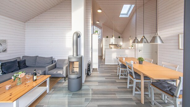 A modern interior with a sofa, dining table, and a wood-burning stove. - Nice home in Krems II/Warderbrück with sauna (Krems II/Warderbrück)