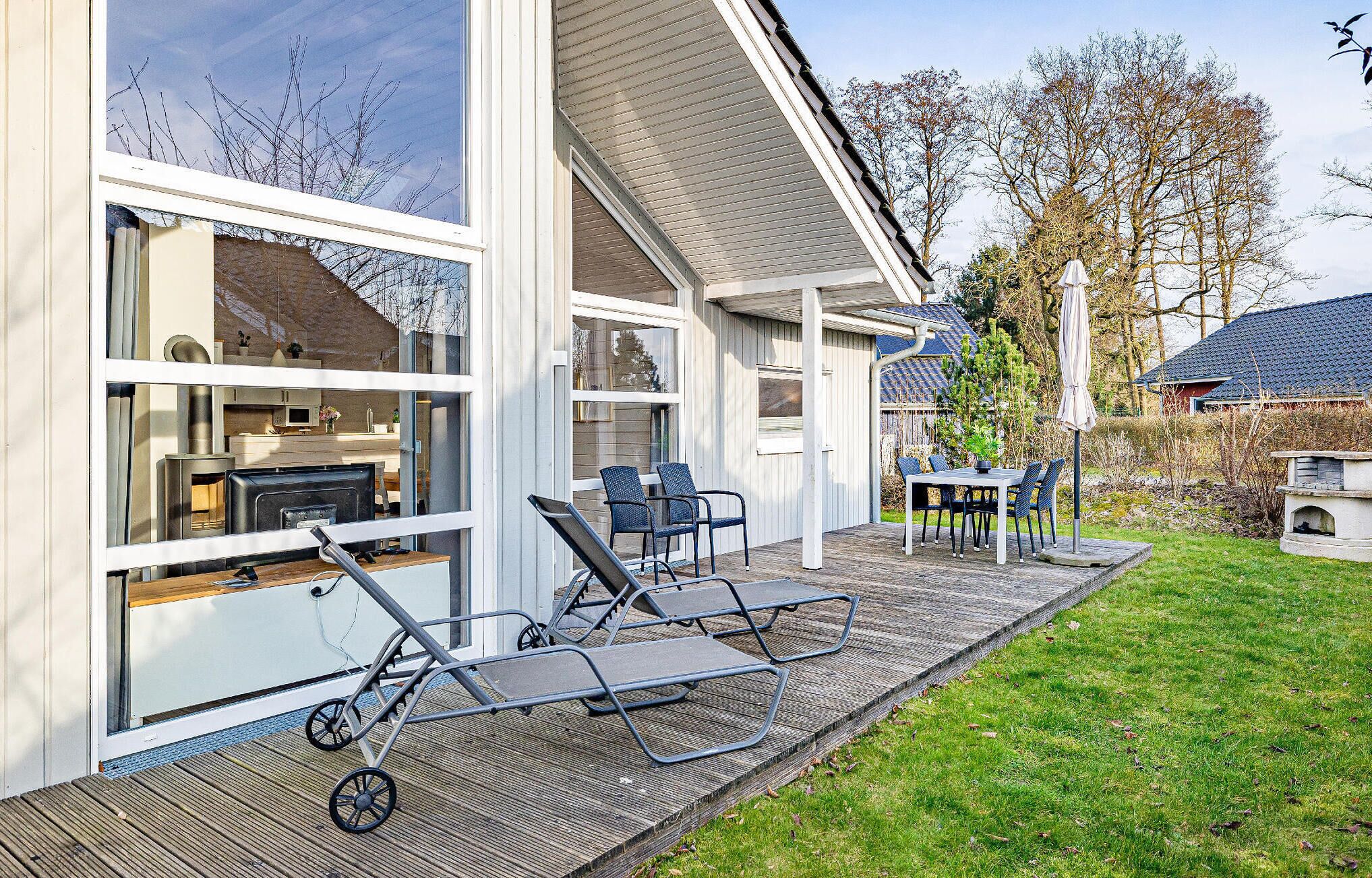 A modern house with a deck, outdoor seating, and a visible kitchen.