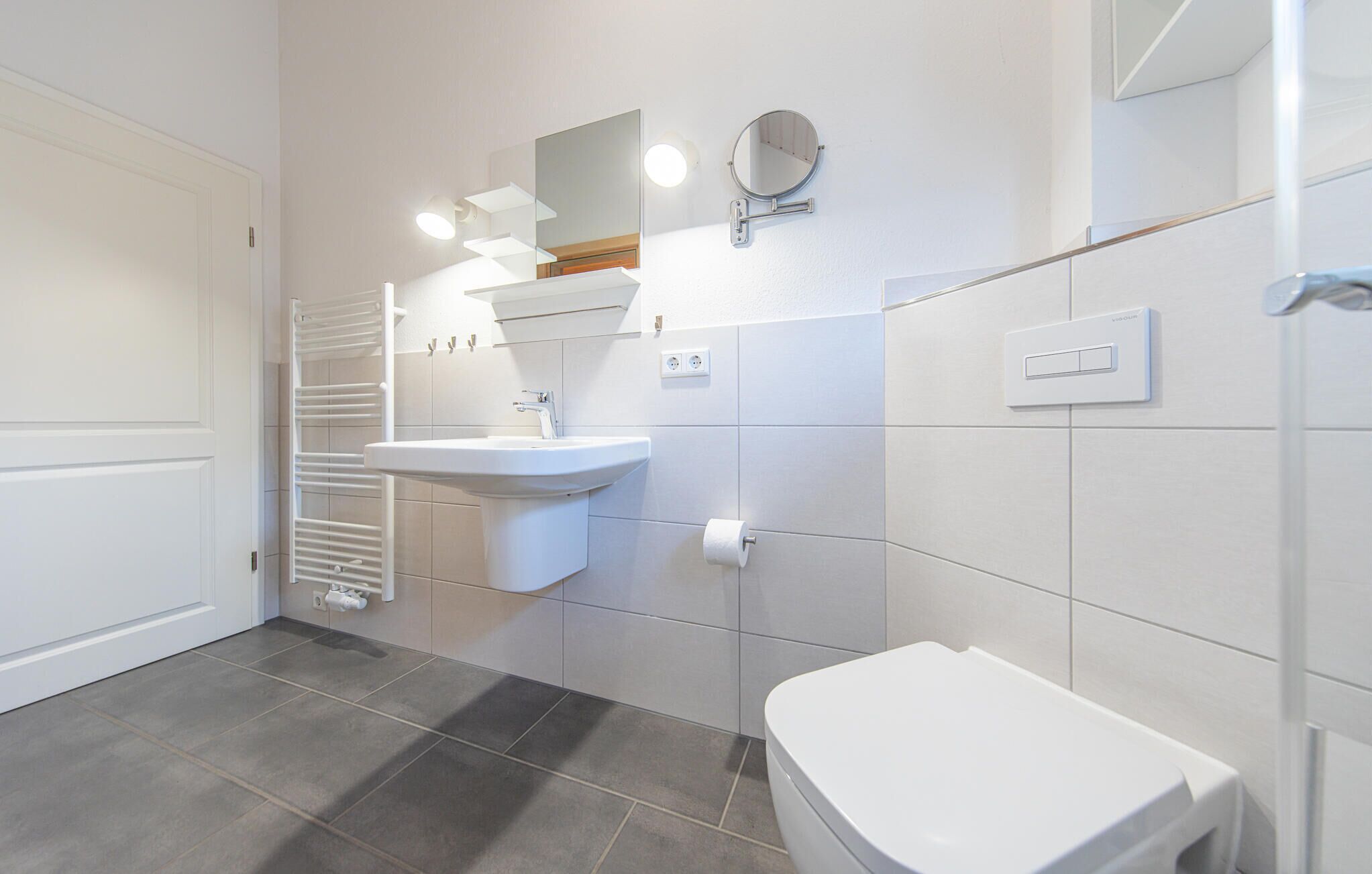 A modern bathroom with a toilet, sink, and towel rack.