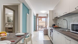 Une cuisine moderne équipée d’une cuisinière, d’un four à micro-ondes et d’un évier intégrés. On y trouve également un coin repas avec une table et des chaises, et une vue sur le balcon extérieur.