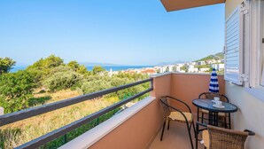 Ein Balkon mit Tisch und Stühlen, mit Blick auf eine Küstenstadt und das Meer.