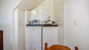 Una cocina compacta con refrigerador, lavamanos y estufa.