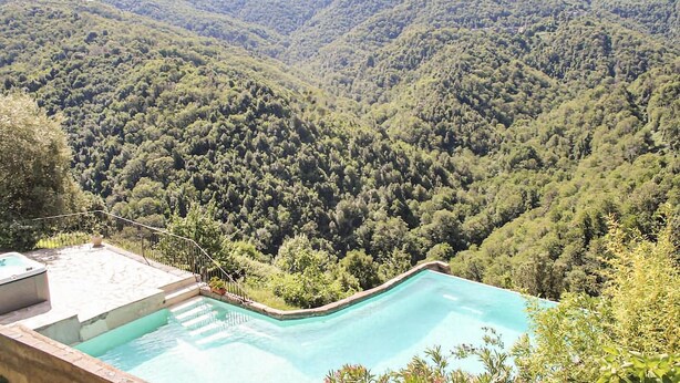 Una piscina con vista a un valle boscoso y montañas.
