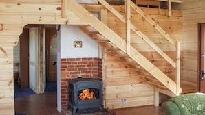 Un interior de madera con chimenea, una escalera y una puerta.