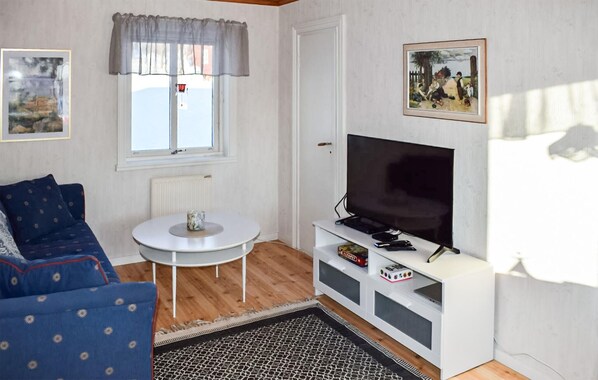A room with a blue sofa, a white table, a TV on a white stand, and a door. - 1 bedroom nice home in öje (Öje)