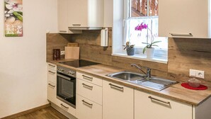 A modern kitchen with a wooden countertop, stainless steel sink, and a built-in oven.