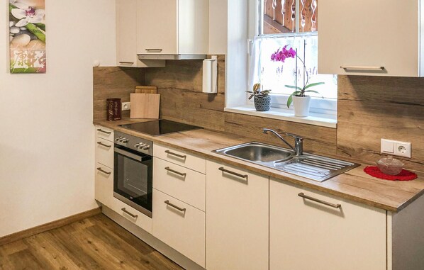 Una cocina moderna con encimera de madera, pileta de acero inoxidable y horno empotrado.