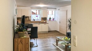 A compact kitchen with wooden cabinets, a built-in oven, and a window with potted plants.